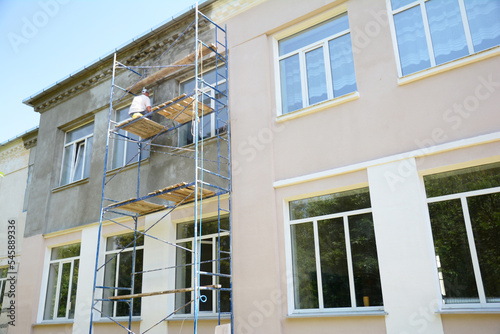 Builder contractor plastering external walls before painting outside house facade. Prepare for painting house exterior walls.