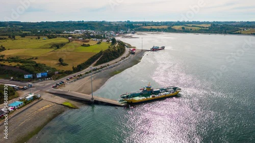Aerial orbital Timelapse showing a ferry loading cars on the Chacao Channel. Looking over the landscape of Chiloe Island. photo