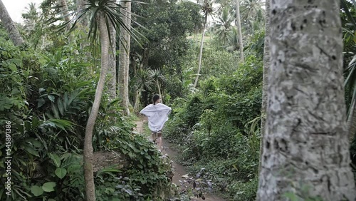 girl walks among dense green jungle, back view photo