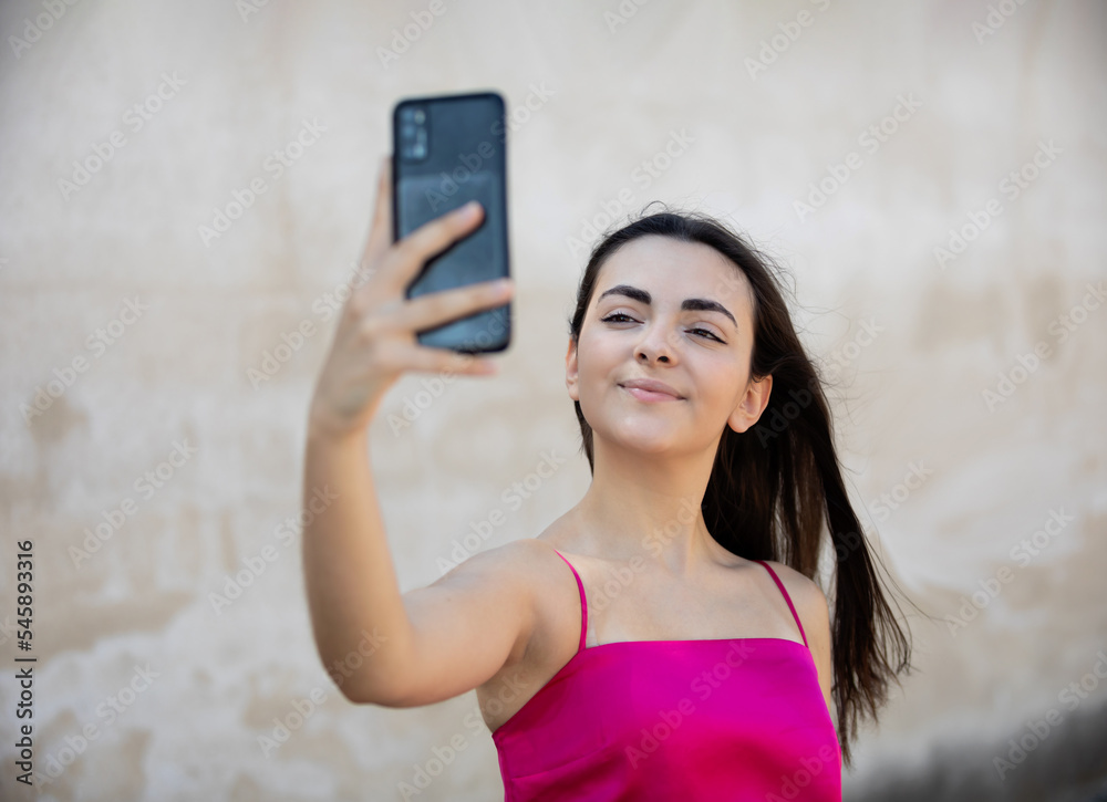 Portrait of beautiful dark-haired teenager woman wearing pink top, looking her mobile phone Portrait of beautiful dark-haired teenager woman wearing pink top, looking her mobile phone