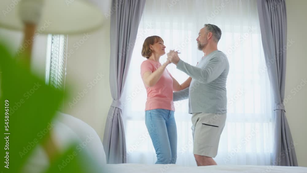 Caucasian senior couple dancing with music together in bedroom at home Caucasian senior couple dancing with music together in bedroom at home