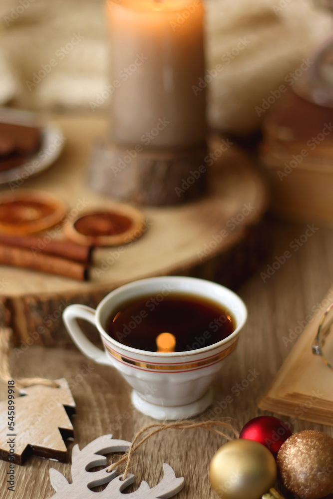 Fototapeta premium Cup of tea or coffee, various sweets and spices, Christmas decorations, comfy blanket, books and glasses. Selective focus.