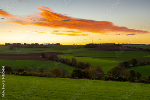Spectacular and colourful sunrise over a rolling hill landscape with winding roads and agricultural fields in the south of Limburg. The landscape reminds of the Tuscan region in Italy.