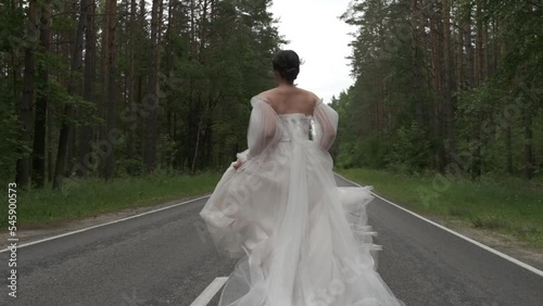 The bride runs along the road and her dress develops