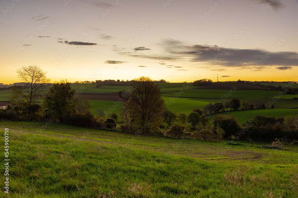 Spectacular and colourful sunrise over a rolling hill landscape with winding roads and agricultural fields in the south of Limburg. The landscape reminds of the Tuscan region in Italy.