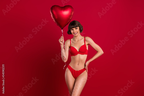 Portrait of attractive cheerful girl holding air ball heart shape 14 February festal time event isolated on bright red color background