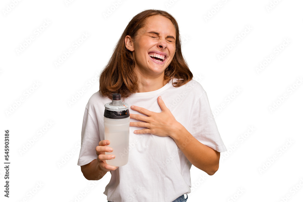 Young caucasian sport woman holding a bottle of water isolated laughs out loudly keeping hand on chest. Young caucasian sport woman holding a bottle of water isolated laughs out loudly keeping hand on chest.