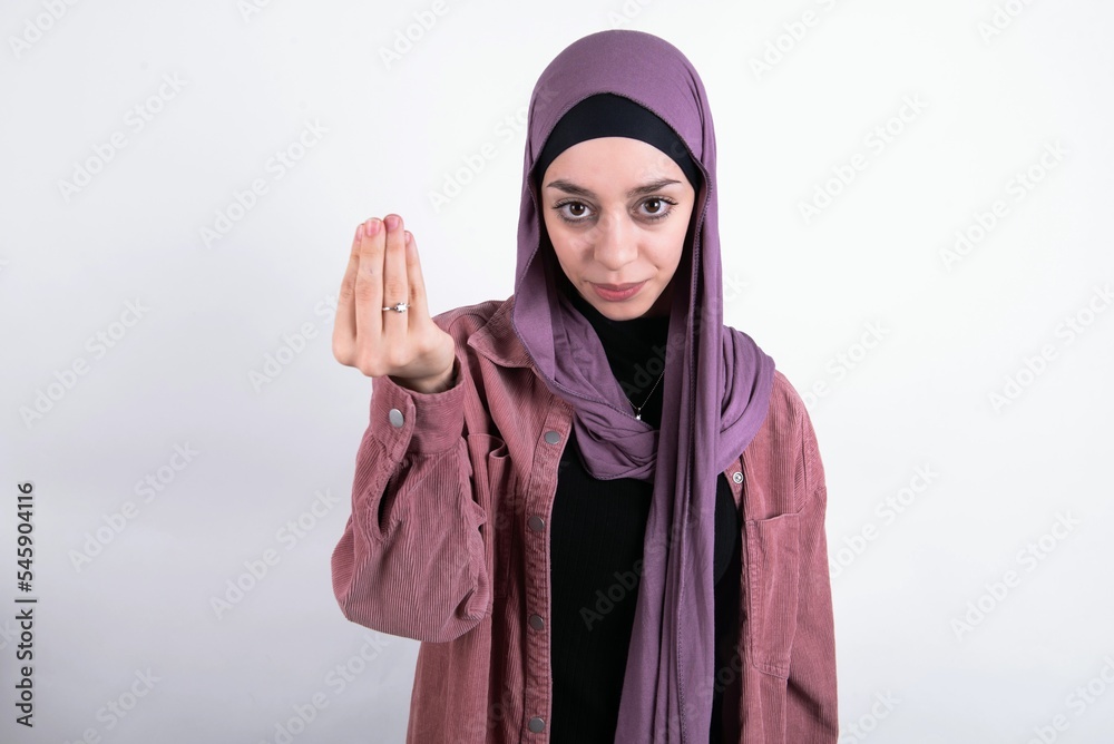 young beautiful muslim woman wearing hijab and pink jacket over white background Doing Italian gesture with hand and fingers confident expression