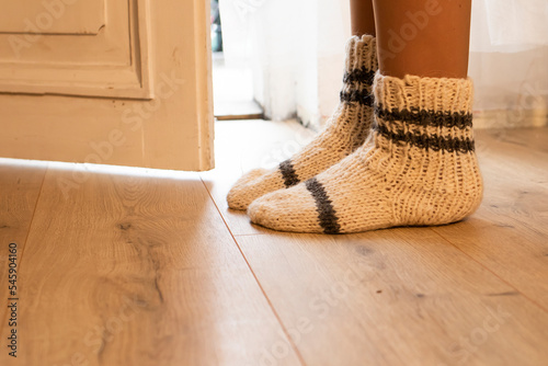 Women's legs in homemade knitted socks on a wooden floor. Side view.
