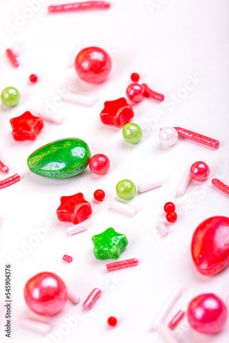 Christmas background of colorful candies. Red and green candies of different shapes on a light background, macro photography
