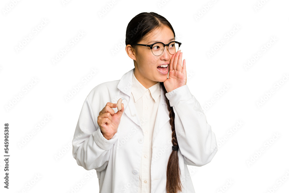 Young asian otorhinolaryngologist woman holding a hearing aid isolated shouting and holding palm near opened mouth. Young asian otorhinolaryngologist woman holding a hearing aid isolated shouting and holding palm near opened mouth.