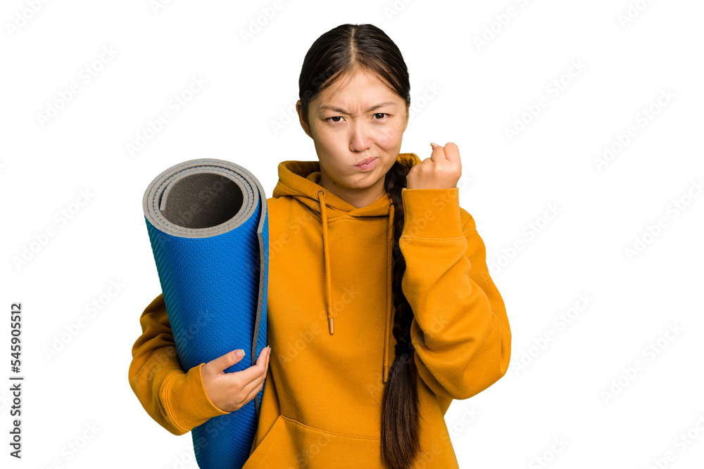 Young asian sport woman holding a mat isolated showing fist to camera, aggressive facial expression. Young asian sport woman holding a mat isolated showing fist to camera, aggressive facial expression.