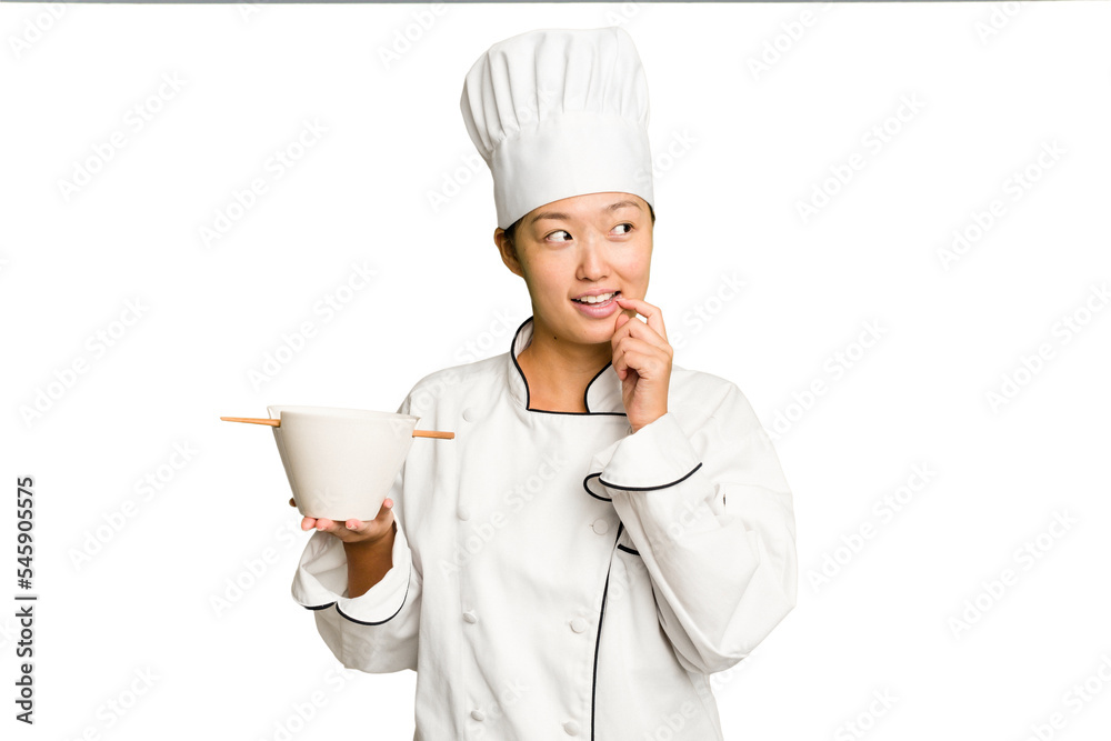 Young chef asian woman holding a bowl of ramen isolated relaxed thinking about something looking at a copy space. Young chef asian woman holding a bowl of ramen isolated relaxed thinking about something looking at a copy space.