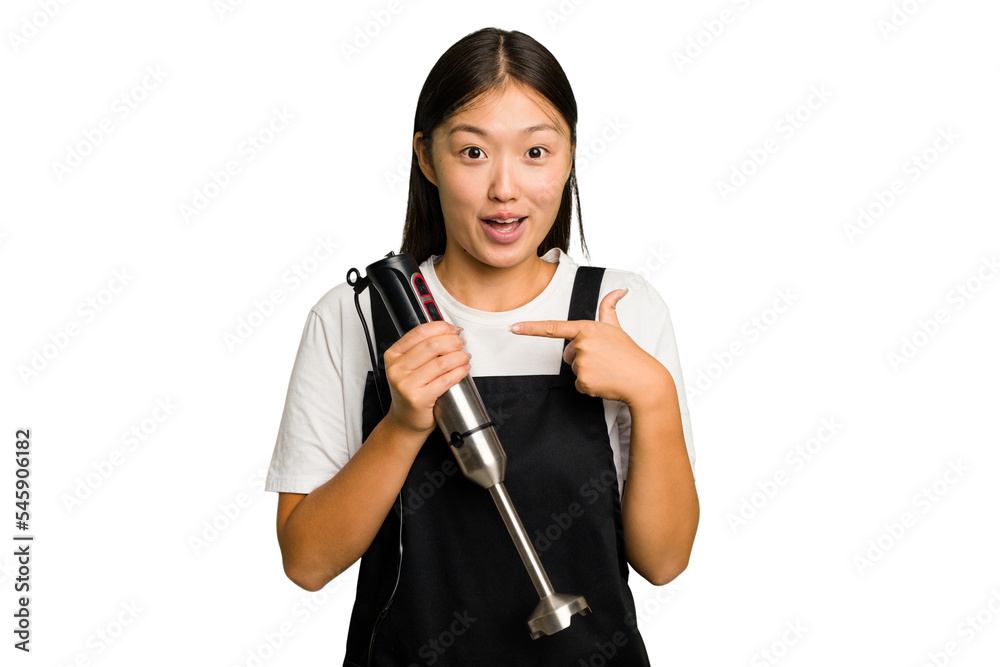 Young asian cook woman holding a blender isolated pointing to the side Young asian cook woman holding a blender isolated pointing to the side