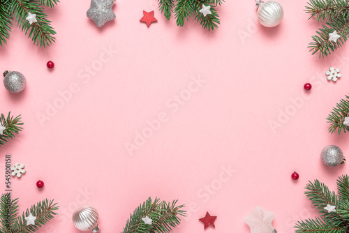 Christmas frame on pink background. Composition made of fir tree, Christmas ornament, red berries. Flat lay. Top view