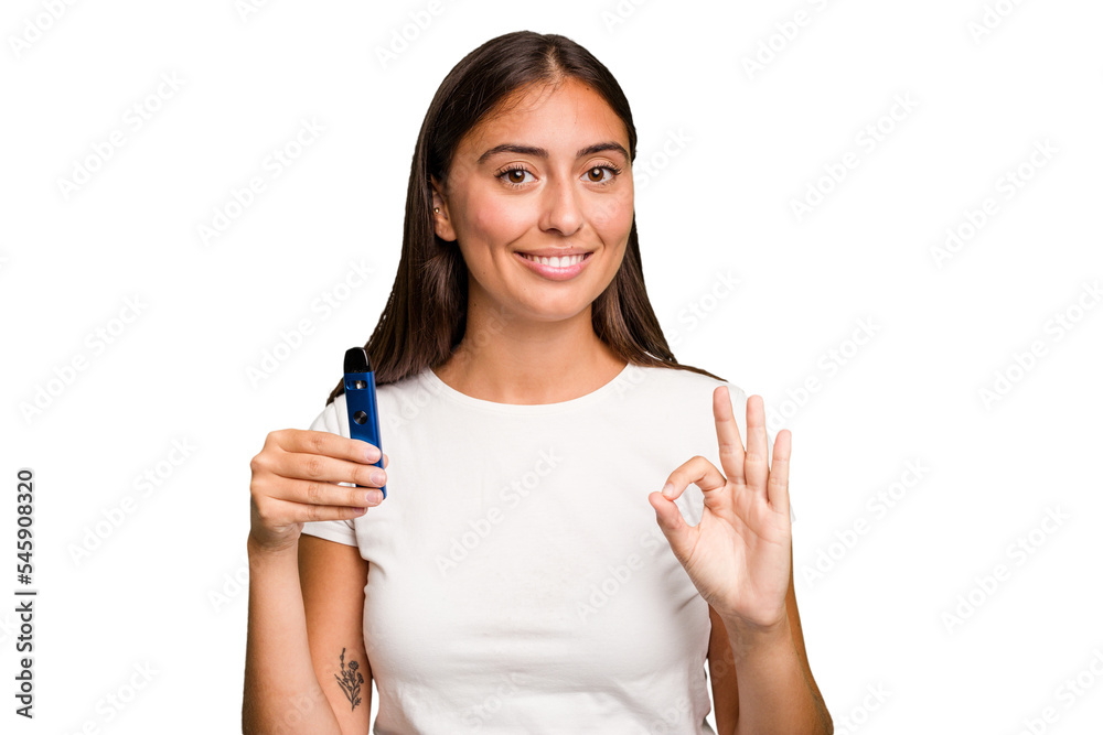 Young caucasian woman holding a electronic cigarette cheerful and confident showing ok gesture. Young caucasian woman holding a electronic cigarette cheerful and confident showing ok gesture.