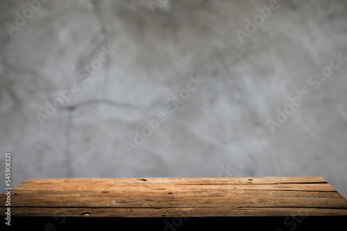 Empty wooden board on table top and blur inside over stucco wall blur background, mock up for display of goods.