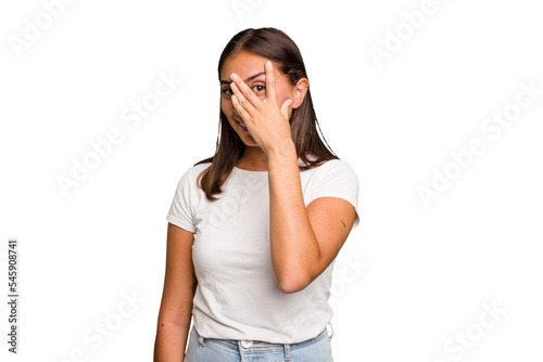 Young cute caucasian woman isolated blink at the camera through fingers, embarrassed covering face.
