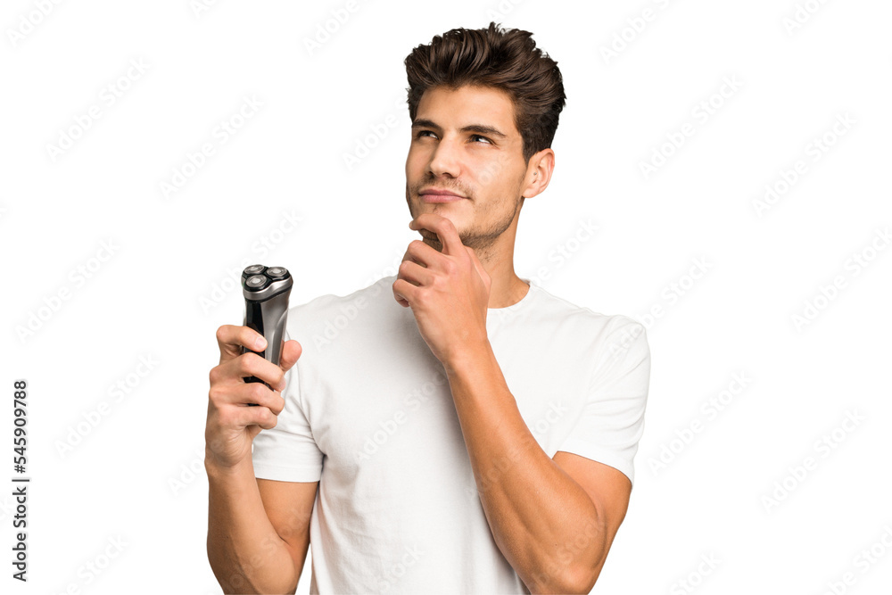 Young caucasian man holding a razor isolated looking sideways with doubtful and skeptical expression. Young caucasian man holding a razor isolated looking sideways with doubtful and skeptical expression.