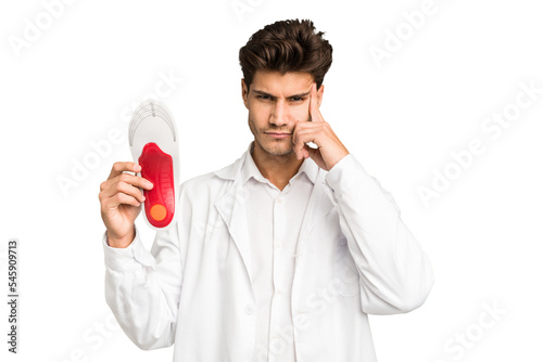 Young caucasian chiropodist man isolated pointing temple with finger, thinking, focused on a task.
