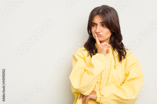 Young Indian woman isolated on white background looking sideways with doubtful and skeptical expression.