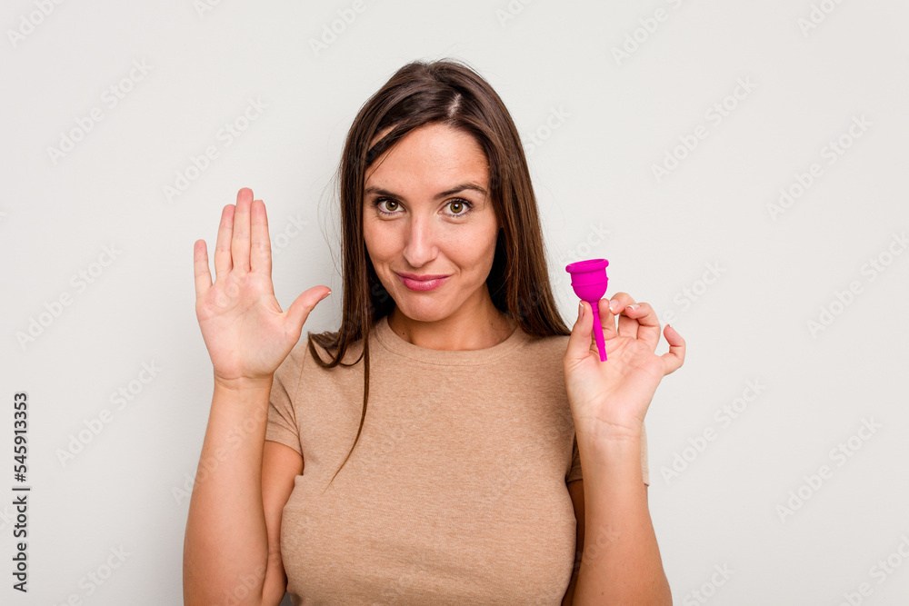 Young caucasian woman holding menstrual cup isolated on white background smiling cheerful showing number five with fingers. Young caucasian woman holding menstrual cup isolated on white background smiling cheerful showing number five with fingers.