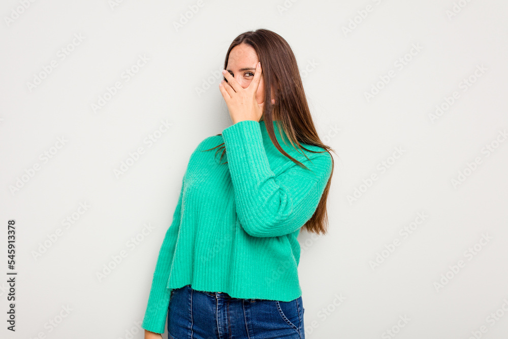 Young caucasian cute woman isolated on white background blink at the camera through fingers, embarrassed covering face. Young caucasian cute woman isolated on white background blink at the camera through fingers, embarrassed covering face.