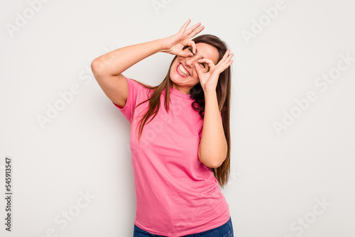 Young caucasian cute woman isolated on white background showing okay sign over eyes