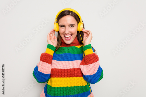 Young caucasian woman listening to music with headphones isolated on white background © Asier