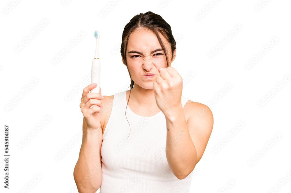 Young caucasian woman holding electric toothbrush isolated on green chroma background showing fist to camera, aggressive facial expression. Young caucasian woman holding electric toothbrush isolated on green chroma background showing fist to camera, aggressive facial expression.