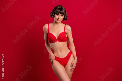 Portrait of attractive feminine fit slim girl posing wearing lingerie isolated over bright red color background