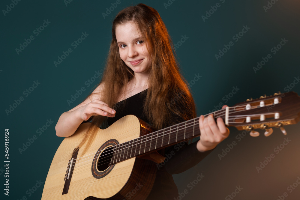 Obraz premium cute young girl playing the guitar on the background.