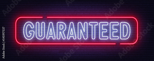 Guaranteed edition neon sign on brick wall background.
