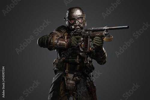 Studio shot of isolated on grey background soldier after armageddon aiming shotgun.