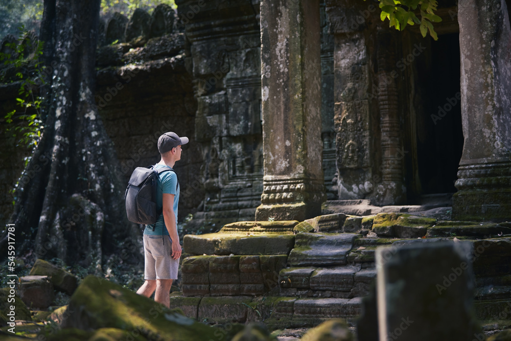 Man with backpack coming to ancient temple. Traveler in Cambodia..