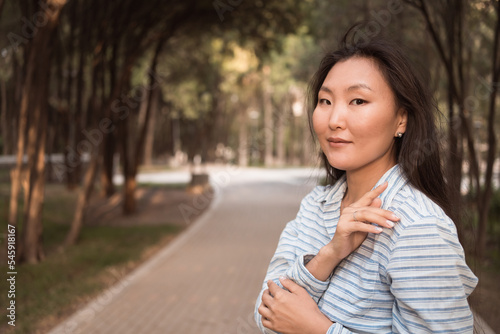 Young asian woman with long black hair posing in city park at summer and looking at camera
