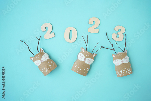 Decorations for Christmas party from toilet roll with the numbers 2023 on a blue background. Easy eco-friendly DIY master class, craft for kids. Development imagination and sensory motor skills