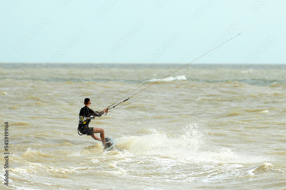 A young kiteboarder rides the waves into the sea