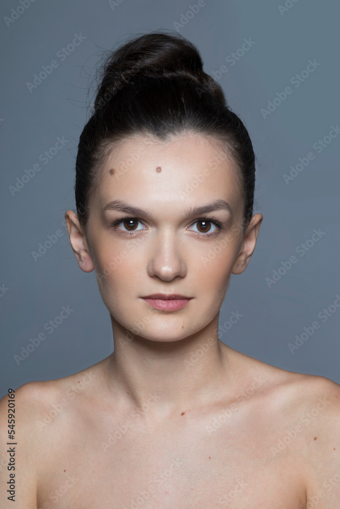 Front closeup portrait of a beauty brunette young woman with makeup and tight hair, isolated grey background. Front closeup portrait of a beauty brunette young woman with makeup and tight hair, isolated grey background.