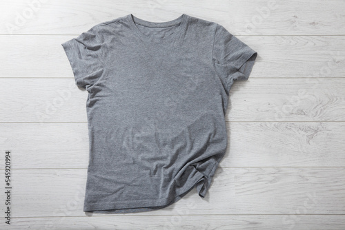 Shirt mockup - pleated, wrinkled t-shirt on white wooden desk top view