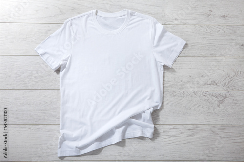 White shirt mockup - pleated, wrinkled t-shirt on white wooden desk top view © missty