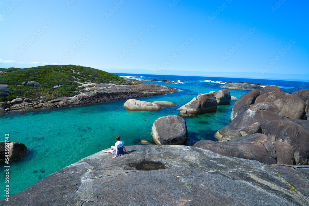 Woman sitting on rocks overlooking blue water Western Australia