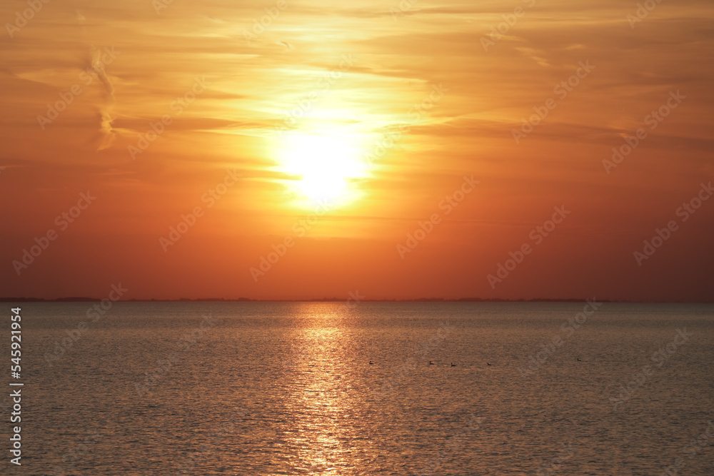 Horizontal photo of the sun setting in the ocean during golden hour