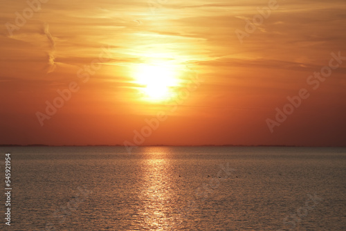 Horizontal photo of the sun setting in the ocean during golden hour © Laura