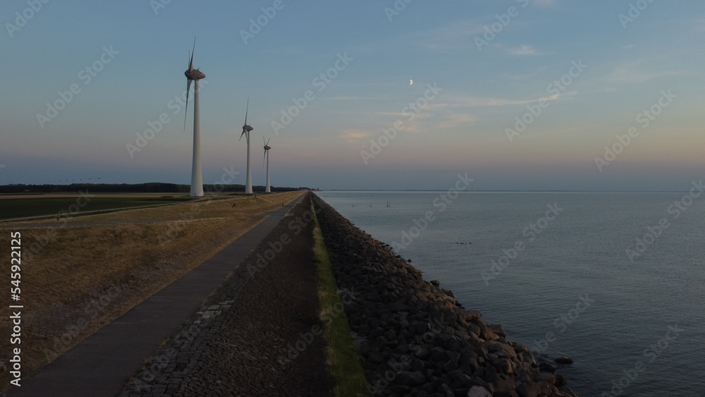 Aerial photo of wind turbines next to the sea during sunset