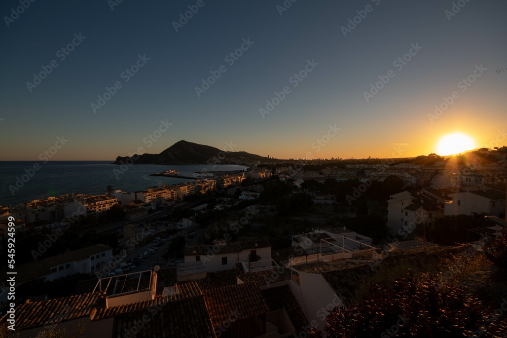 Panorámica del pueblo de Altea en Alicante en la hora dorada del día, el atardecer viendo el mar y la montaña del pueblo con todas las casas del pueblo iluminadas.
