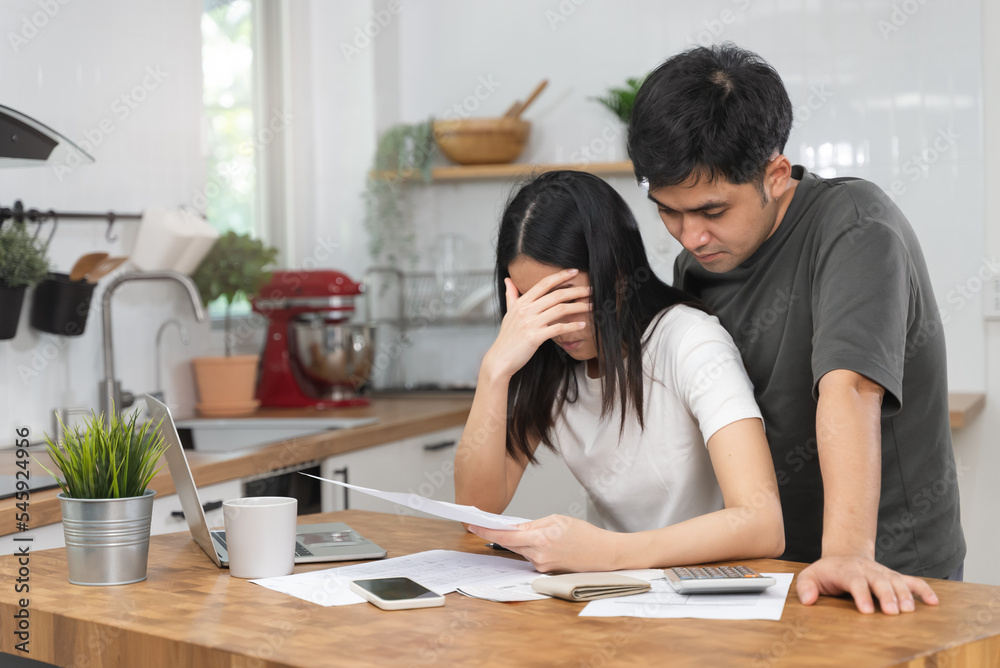 Stressed Asian couple reading notice mail from the bank about unpaid house mortgage Stressed Asian couple reading notice mail from the bank about unpaid house mortgage