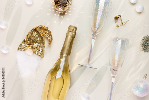 Minimal New Year flat lay, white sparkling wine, trend glasses, champagne bottle, dwarf dress, beautiful shadow, trendy color, beige golden monochrome aesthetic layout, new year holiday event