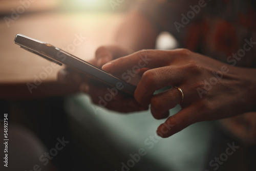 Close-up of woman's hand using a smartphone during coffee break.