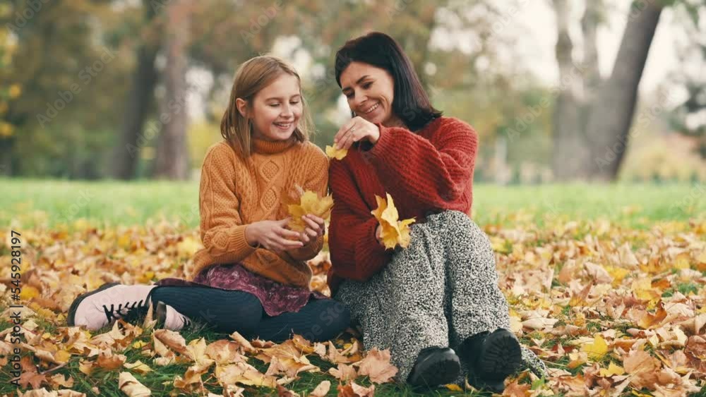 Mother and daughter having fun in autumn park. Happy family playing with fallen foliage outdoors. Mother and daughter having fun in autumn park. Happy family playing with fallen foliage outdoors.